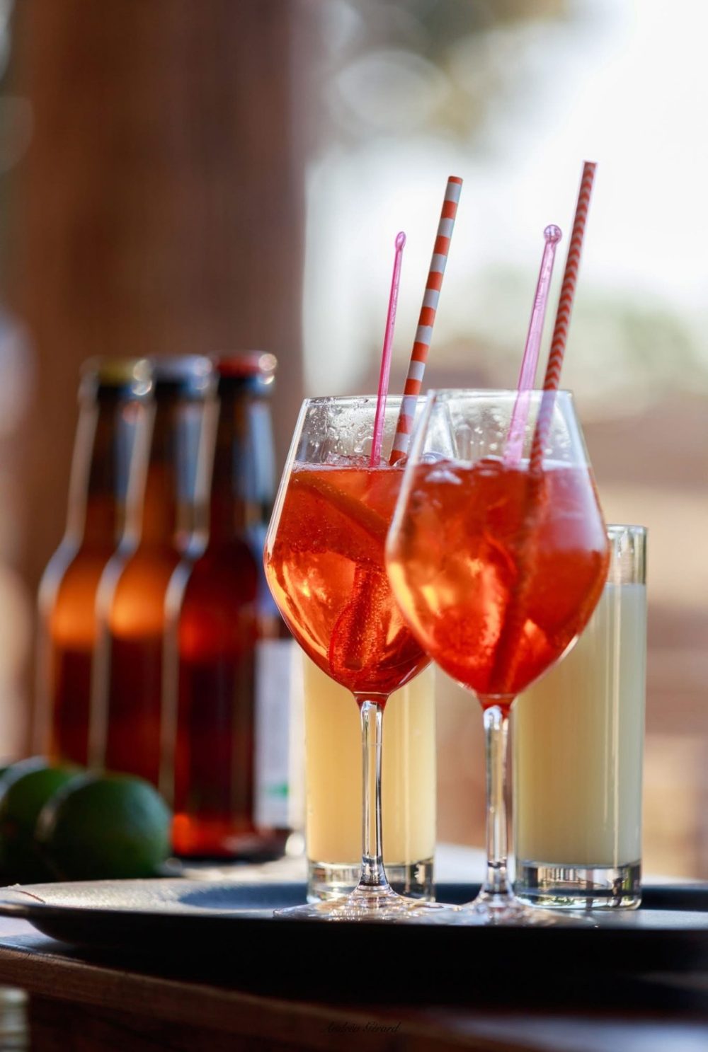 Deux verres de spritz orange et des bières artisanales sur un plateau