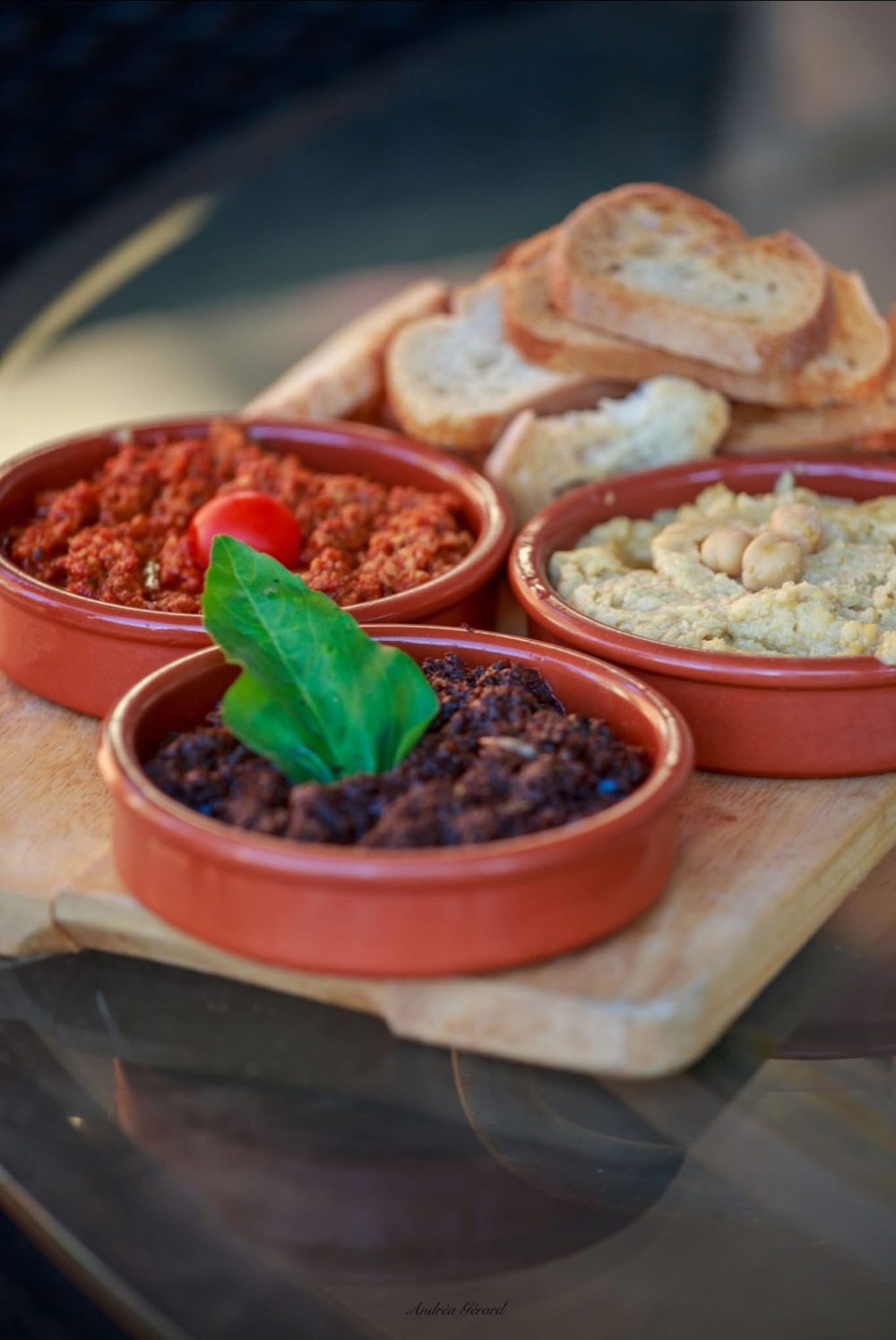 Trois petites cassolettes de tapas avec du pain grillé : tomate, houmous et haricots